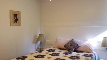 Une chambre à coucher avec un lit, un ventilateur de plafond, une table de chevet et une lampe.