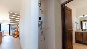 A modern bathroom with a wooden door, a built-in sink, and a large mirror. - Pico del Punto • New Penthouse with Panoramic Views, Surf Access & Rooftop Deck (Los Cerritos)