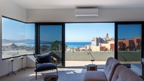 A modern living room with a large balcony, a sofa, a chair, and a small table.