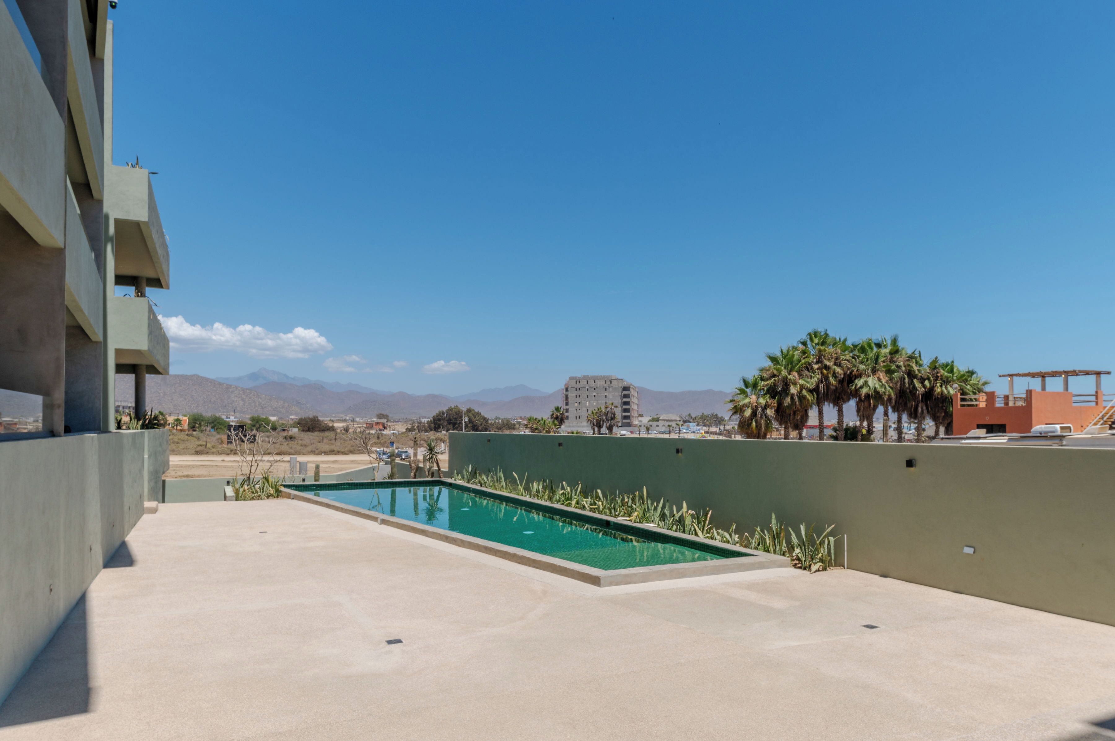 Una piscina sul tetto con vista chiara sulle montagne e un edificio moderno sullo sfondo.