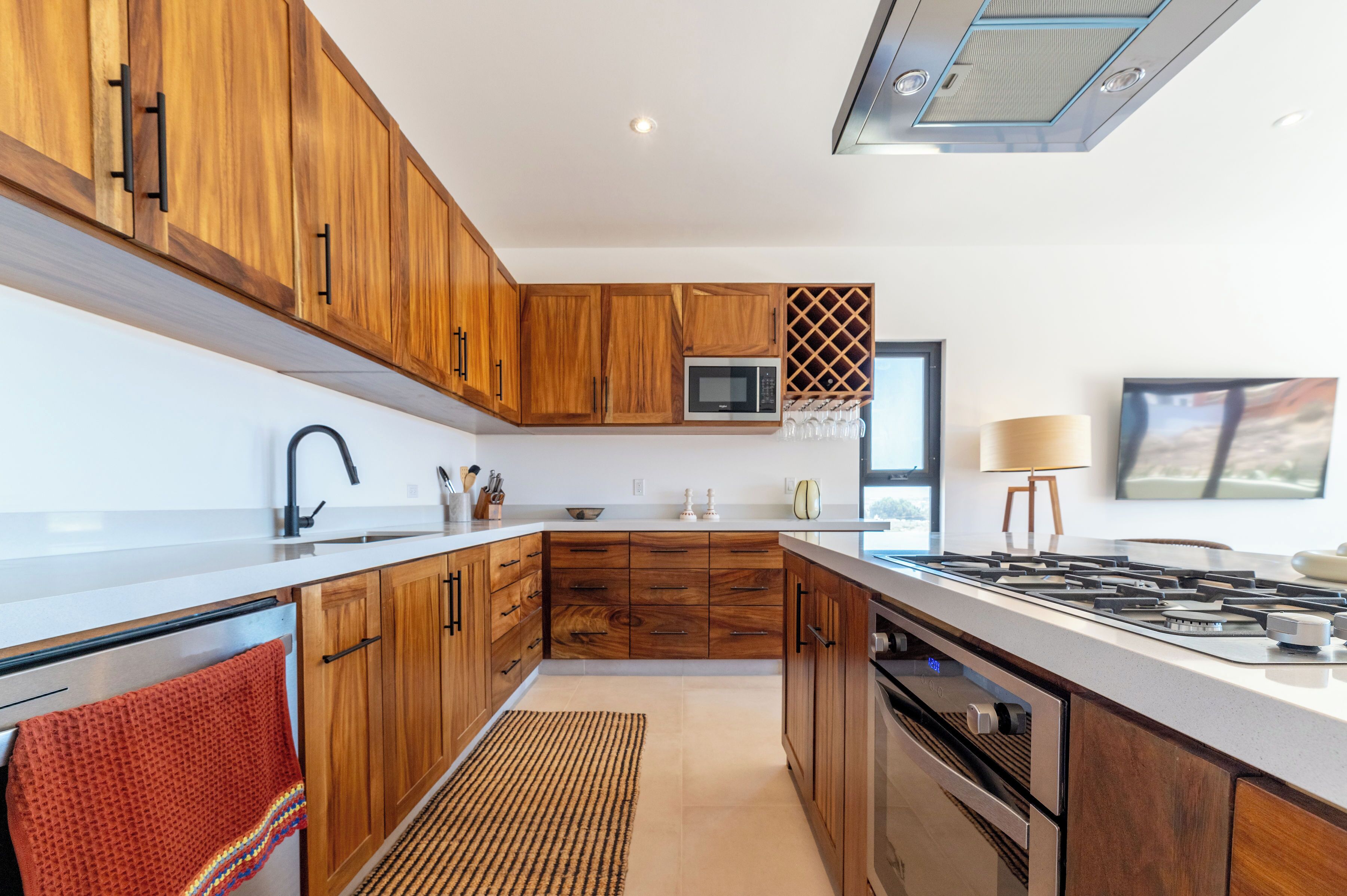 Una cucina moderna con mobili in legno, un forno a microonde, un piano cottura a gas e un'ampia finestra.