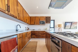 Una cocina moderna con armarios de madera, microondas, cocina a gas y un amplio ventanal.