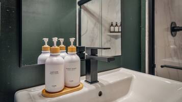 A bathroom sink with hand soap and lotion bottles.