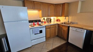A compact kitchen with wooden cabinets, a white refrigerator, an oven, a dishwasher, and a sink. - Feel cozy and at home! Perfect Location For Exploring! (Provo)