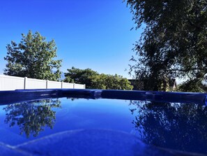 Ein klarer, blauer Himmel mit einem weißen Zaun und Bäumen im Hintergrund.