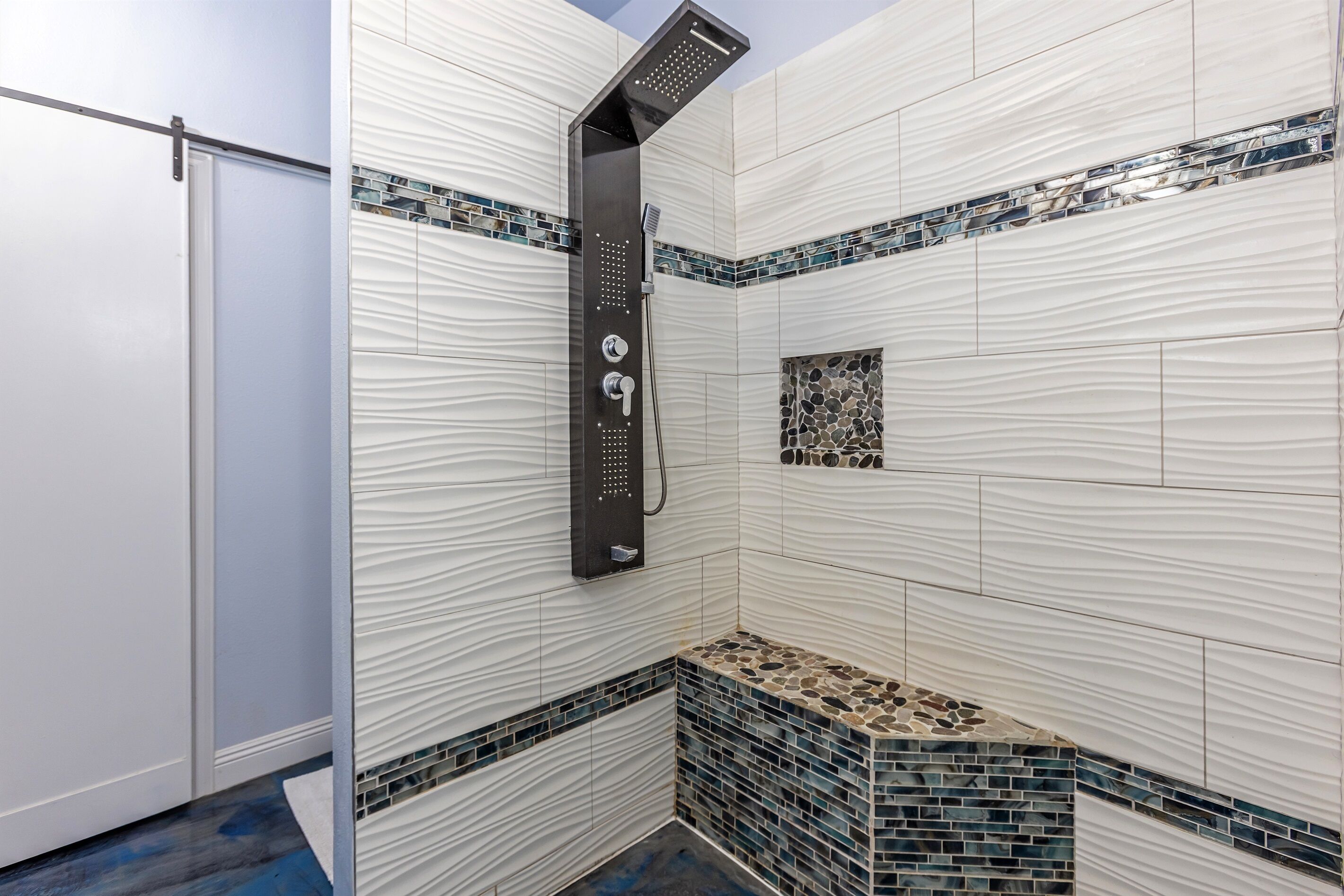 Une salle de bain moderne avec une douche, des murs carrelés et un motif décoratif en mosaïque.