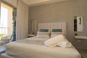 A bedroom with a large bed, two bedside tables, a mirror, and a view of greenery outside. - Comfortable 1BR apt, swimming pool (Playa Juan Dolio)