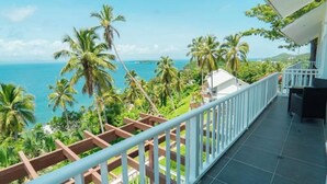 Un balcone con vista sull'oceano e palme.