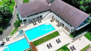 Un grande edificio con piscina, area salotto esterna e patio coperto.