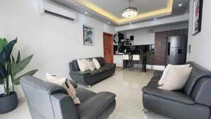 A modern living room with two sofas, a dining area, and a kitchen in the background.
