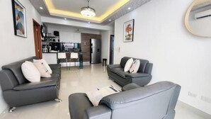 A modern living room with two sofas and a coffee table, a kitchen in the background, and a dining area.