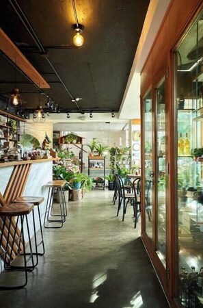 L'intérieur d'un café moderne, avec un bar, des tables et des chaises, ainsi que des plantes en pot.
