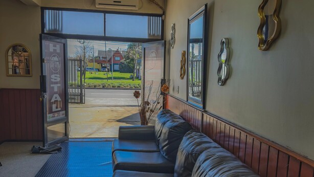 Vestíbulo de hotel con mostrador de recepción, zona de espera con sofás de cuero y vista a la calle.