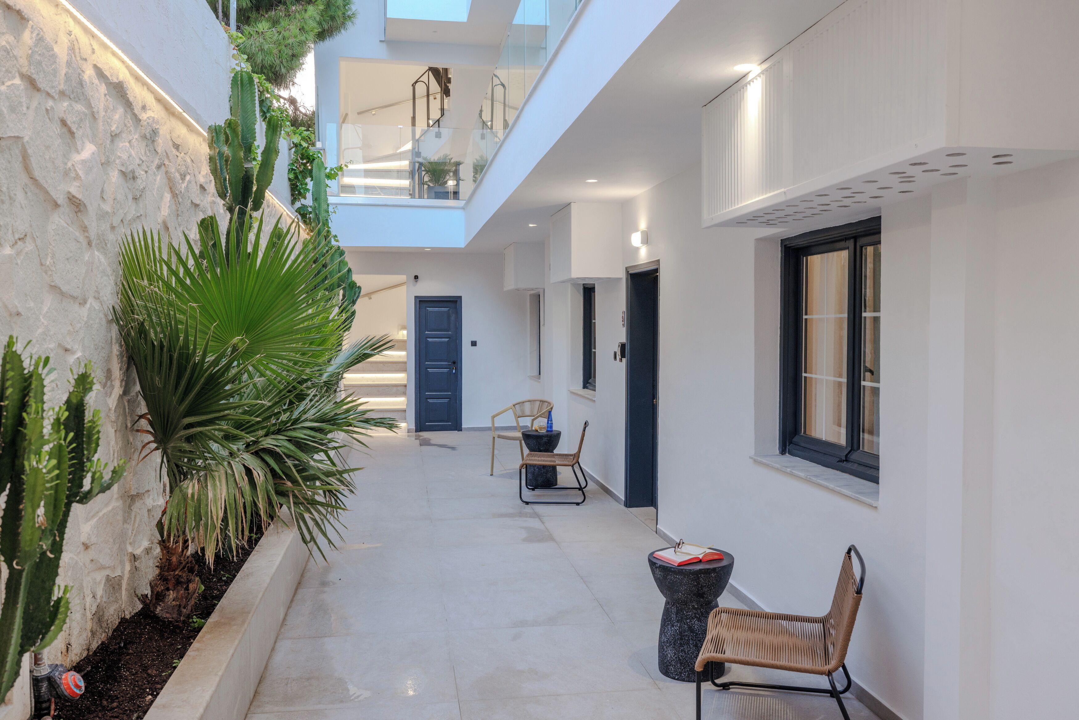 A modern interior with a central hallway, a staircase, and a seating area with a table and chairs.