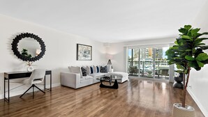 A modern living room with a white sofa, a black-framed mirror, a glass coffee table, and a large potted plant. - The Mahogany' Full Boats View Marina Front Row Dream Pool, Jacuzzi And Gym (Marina del rey)