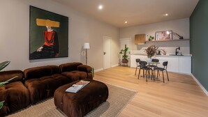 Ein modernes Wohnzimmer mit einem großen Gemälde, braunen Sofas und einem Essbereich mit Stühlen und einem Tisch.