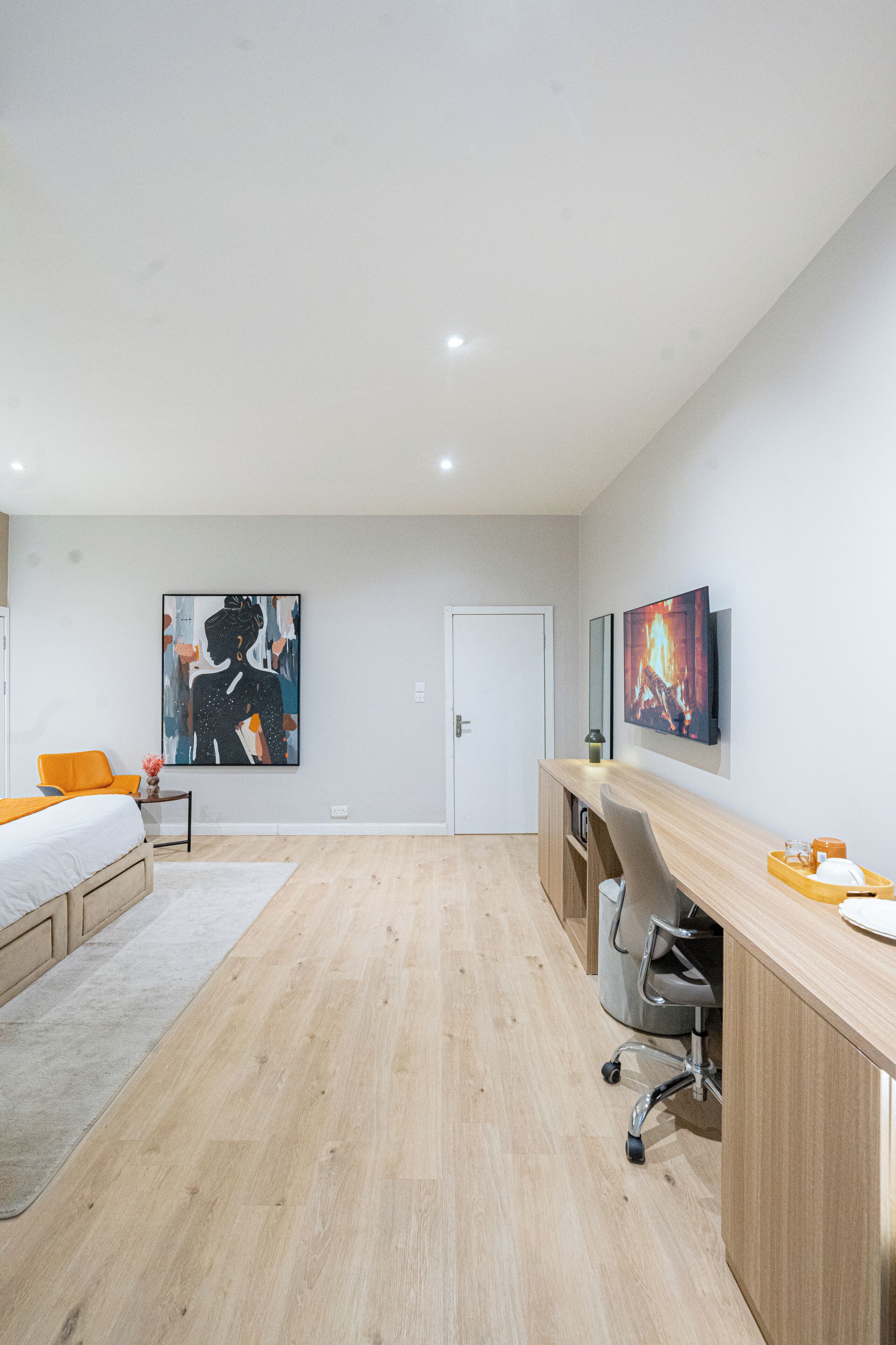 Een moderne slaapkamer met een bed, bureau en stoel, en kunstwerken aan de muur.