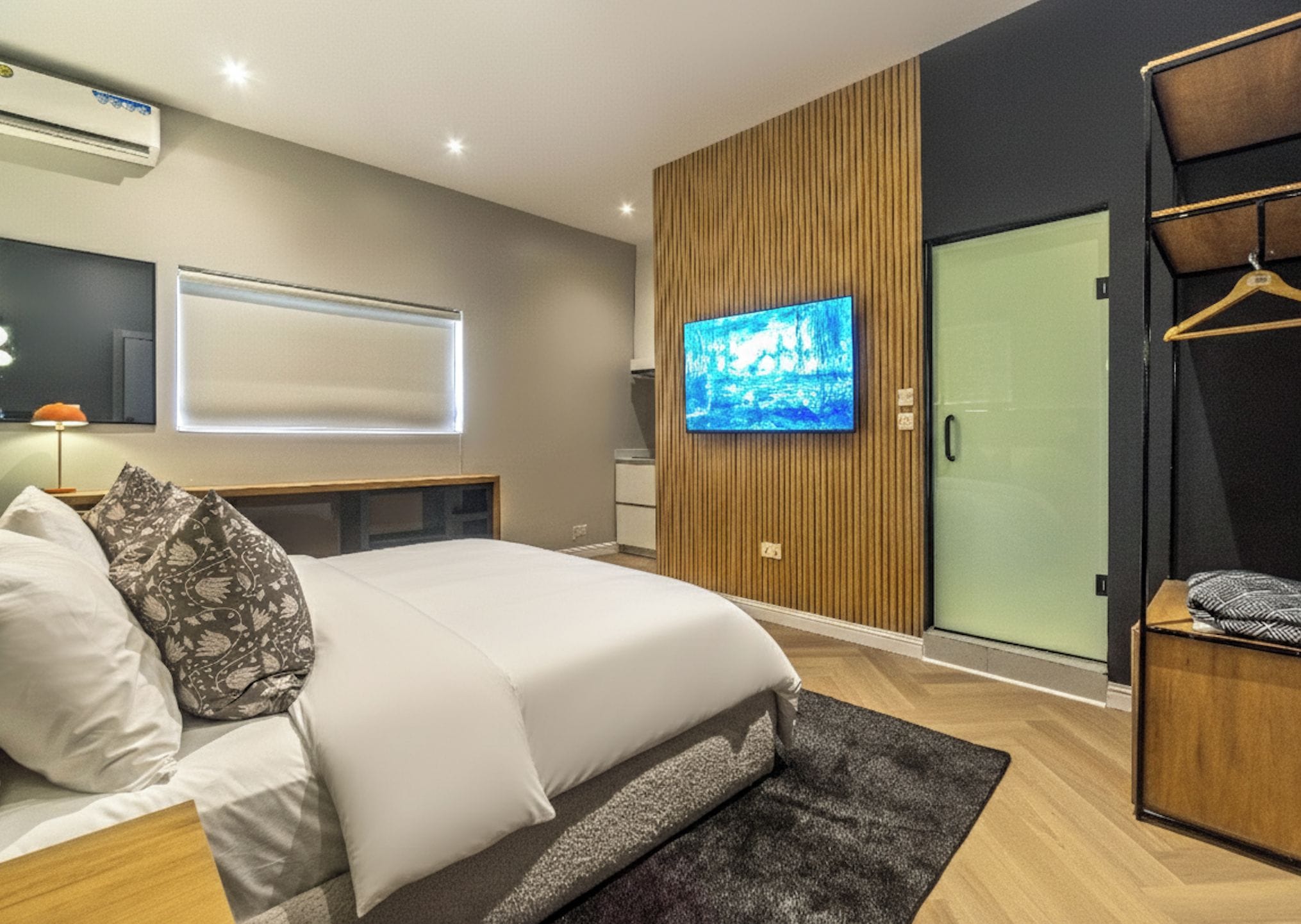 A modern bedroom with a bed, a television, a wardrobe, and a sliding door.