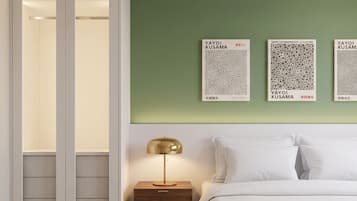 A bedroom with a bed, nightstand, lamp, and wall art.