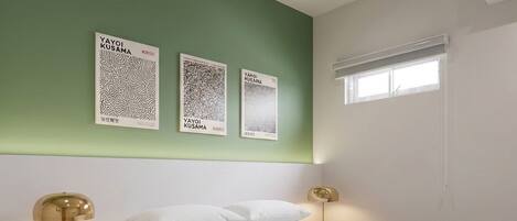 Une chambre à coucher avec un lit, deux tables de chevet et des œuvres d’art murales.
