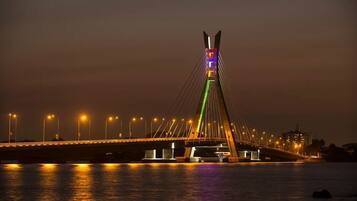 A cable-stayed bridge at night with illuminated cables and lights reflecting on the water.