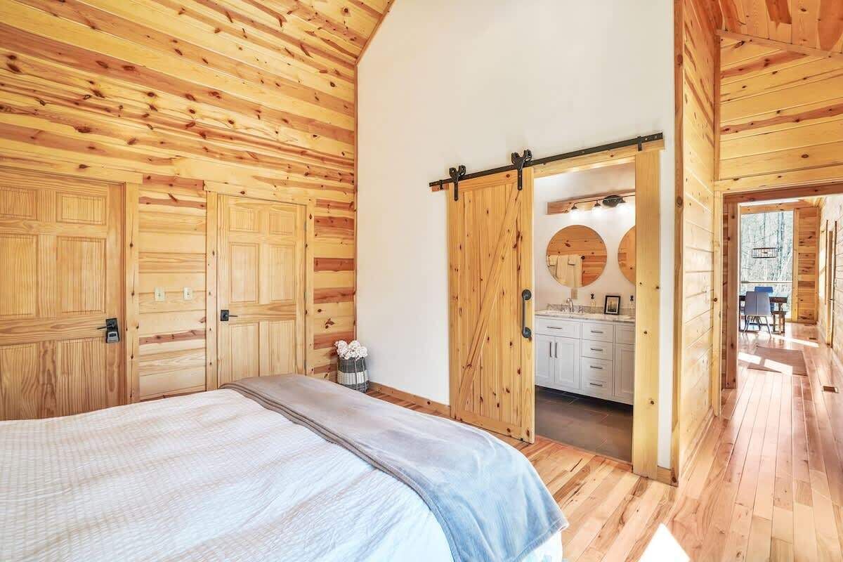 Una habitación con paneles de madera, una cama, una puerta corredera que da a una cocina y un ventanal circular.
