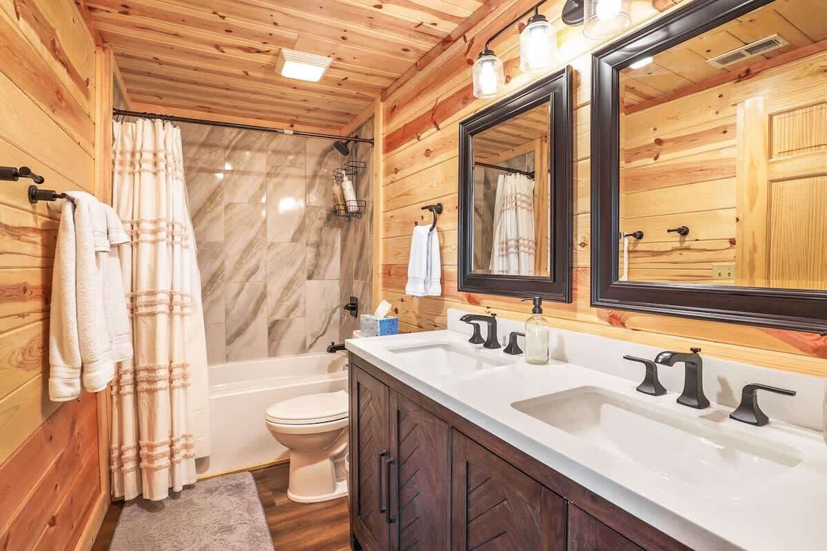Un baño rústico con cabaña que incluye ducha, inodoro y un espejo grande.
