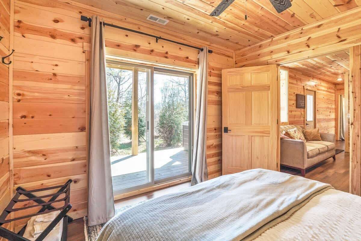 A wooden cabin interior with a bed, a window, and a sofa.