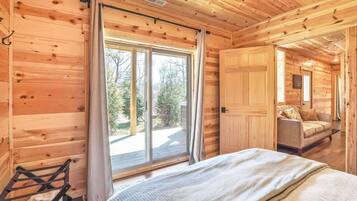 A wooden cabin interior with a bed, a window, and a sofa.