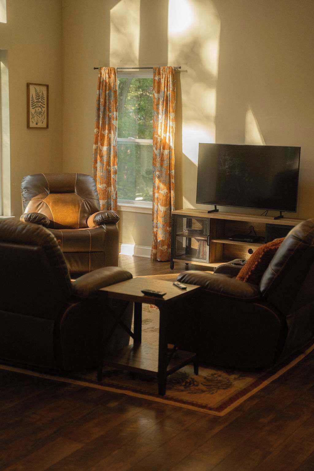 A living room with a leather sofa, a coffee table, and a flat-screen TV.