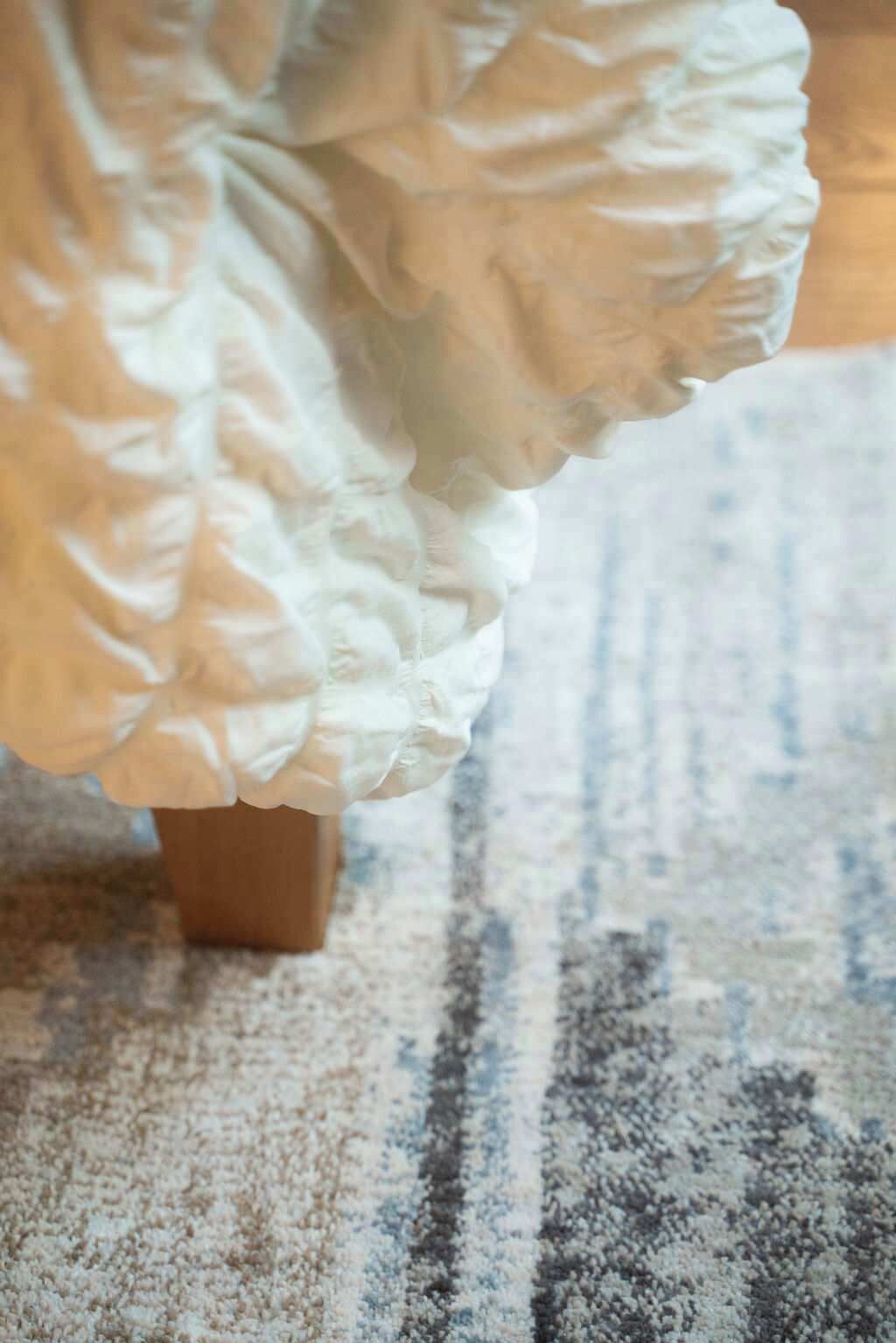 Gros plan sur un tissu blanc à volants, qui pourrait faire partie d’un vêtement ou d’un élément de décoration, posé sur un support en bois.