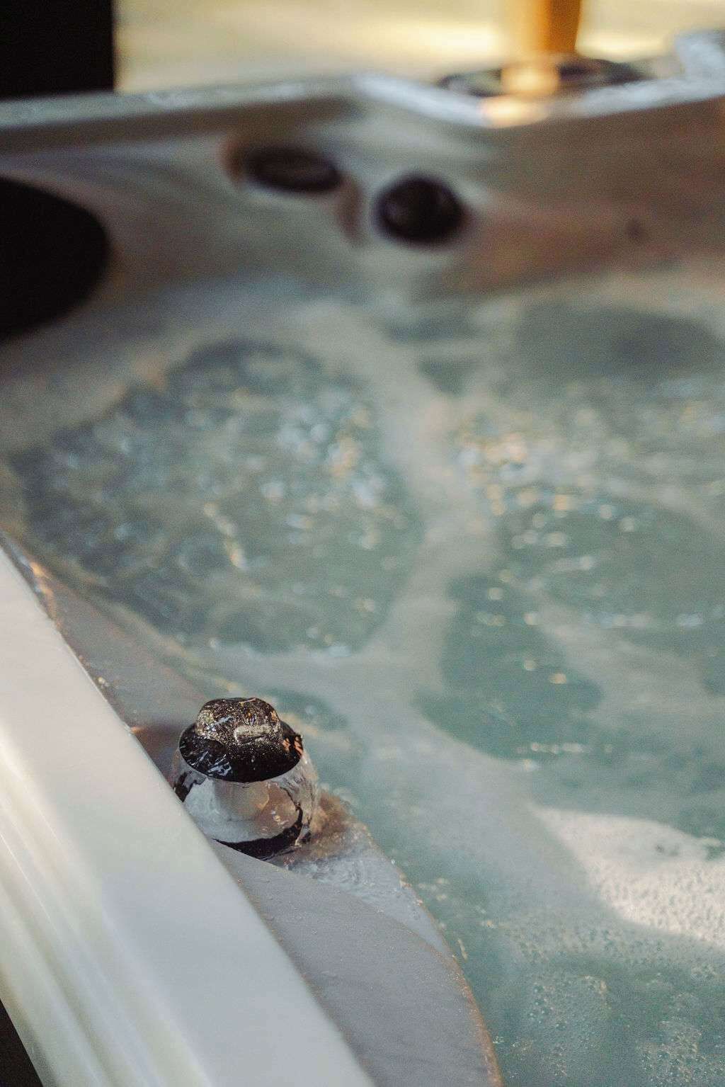 A hot tub with visible bubbles and a single person sitting in it.