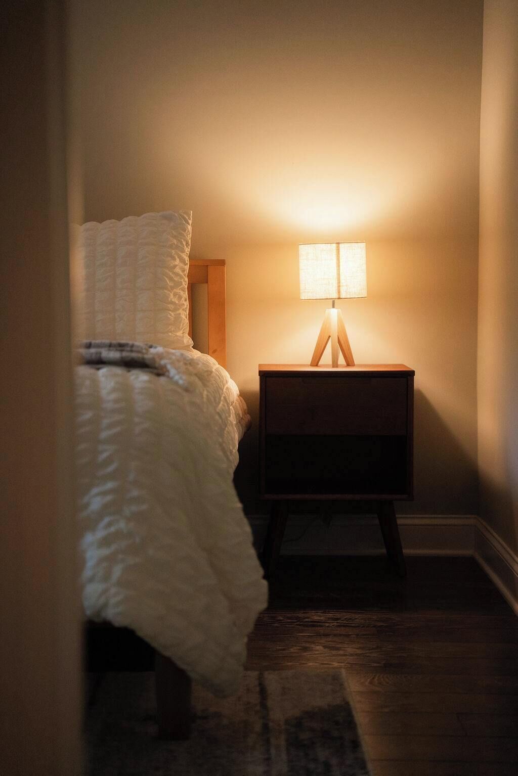 Een slaapkamer met een bed, een nachtkastje met een lamp en een nachtkastje.