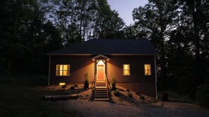 A two-story house with a front porch, a visible staircase, and a driveway leading to the entrance. - Modern 2 BD Cabin With hot tub & Games & Central Loc (Rockbridge)