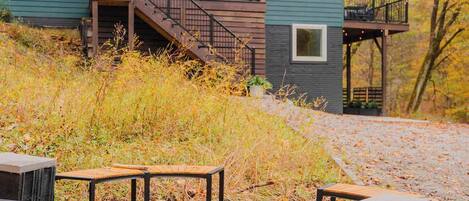 A two-story cabin with a wooden deck and a fire pit.