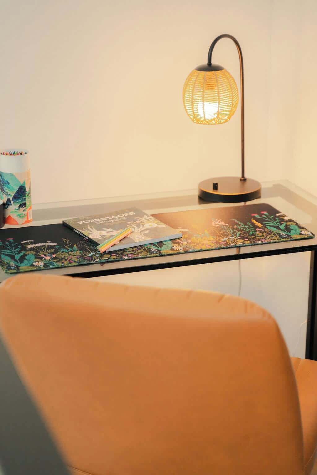 A study area with a glass table, a chair, a lamp, and a notebook.
