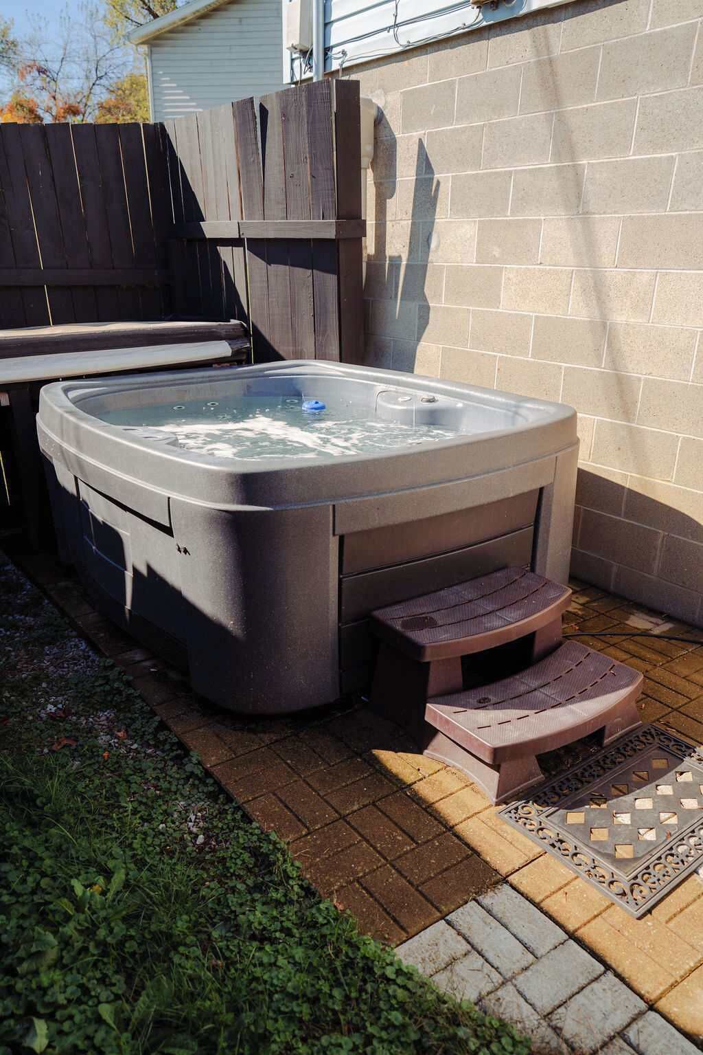 Ein Whirlpool mit Stufen, einer Holzterrasse und einer Ziegelwand.
