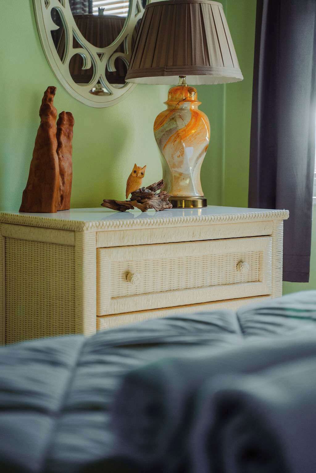 Una habitación con cama, una lámpara en una cómoda y un espejo en la pared.