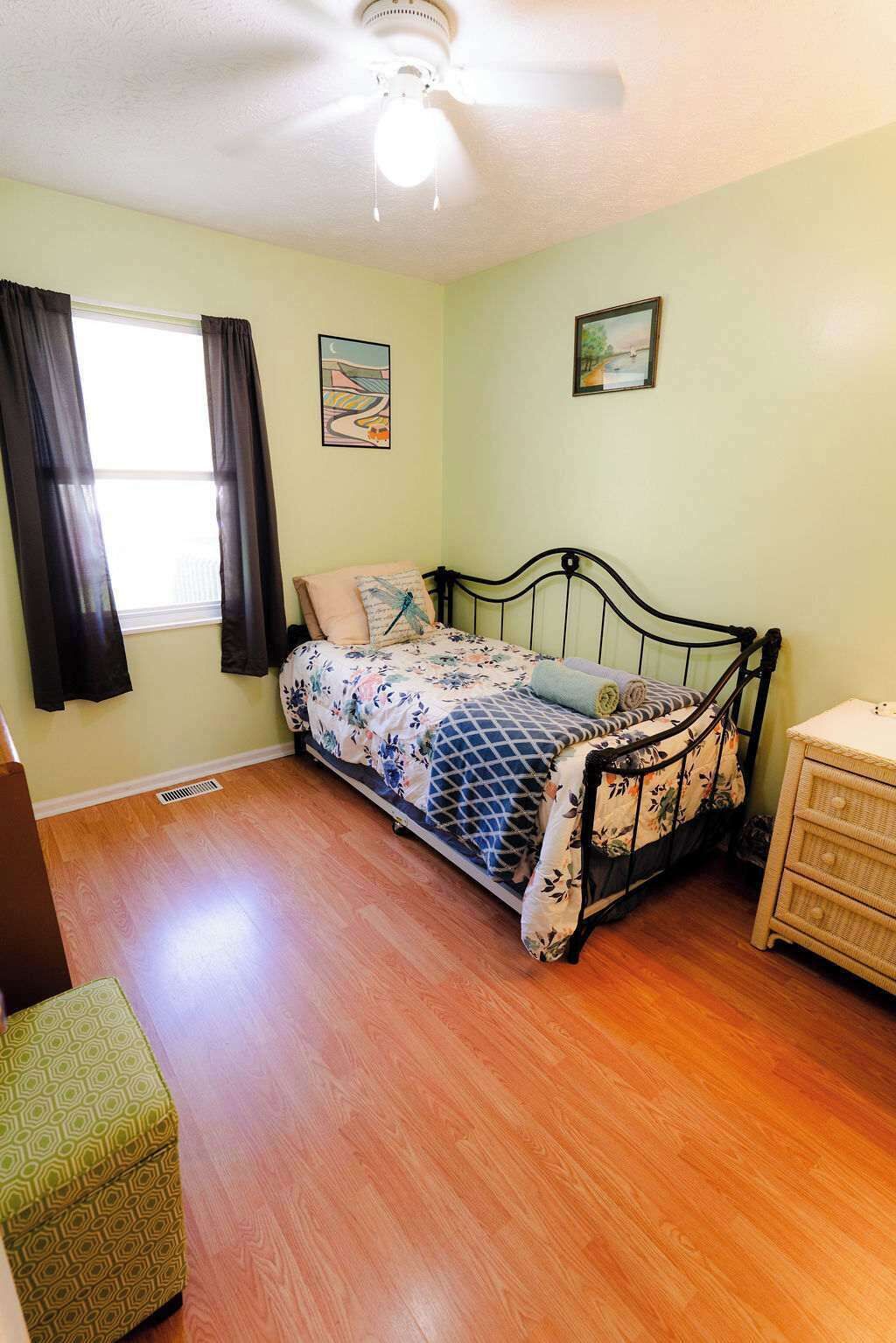 A bedroom with a bed, a dresser, a chair, and a ceiling fan.