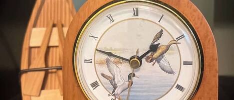 A wooden clock with Roman numerals and a depiction of ducks on its face.