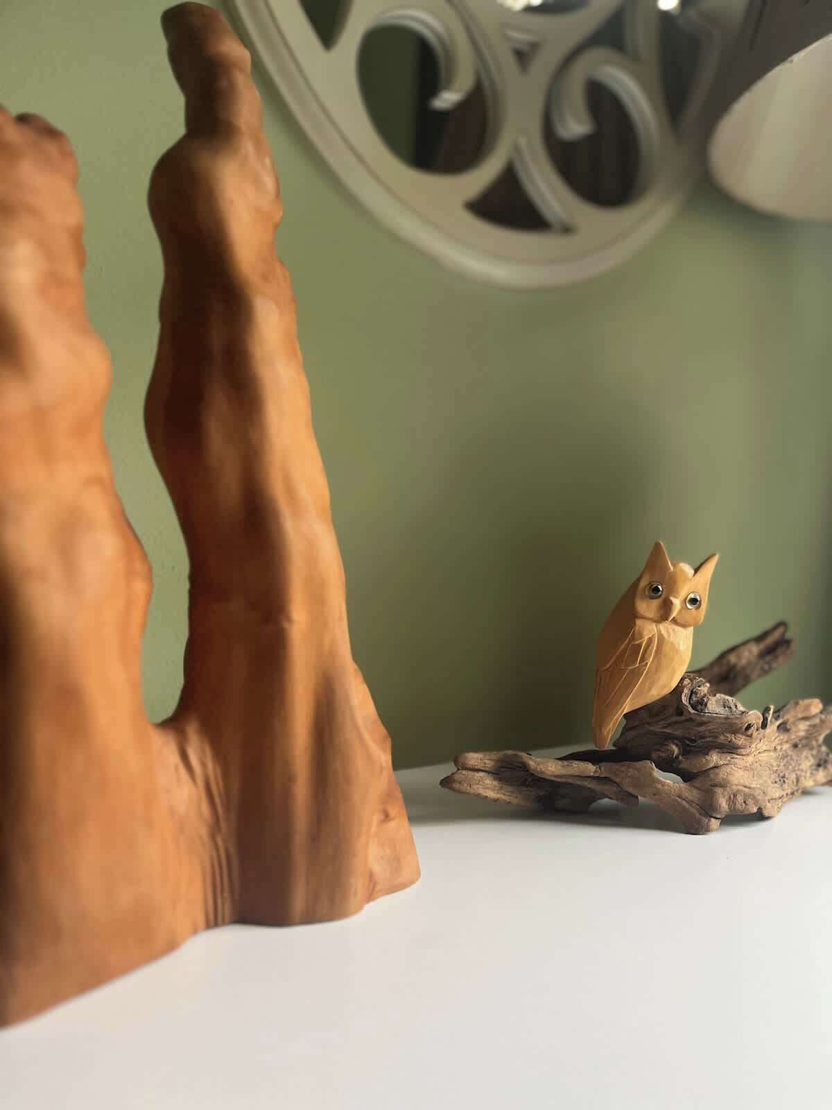 Una escultura de madera de un ave posada en una rama.