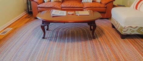 A living room with a brown leather sofa, a wooden coffee table, and a patterned rug.