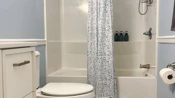 A bathroom with a toilet, a shower with a curtain, and a bathtub.