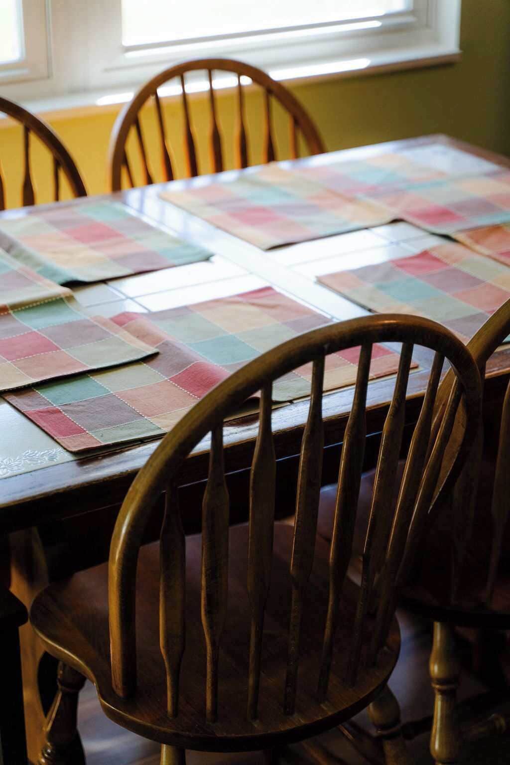 Una mesa de comedor con camino de mesa acolchado y sillas de madera.