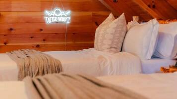 Un dormitorio acogedor en el ático con vigas de madera, dos camas y un letrero de neón que dice "WILD WEST".