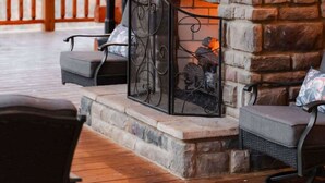 Una chimenea de piedra con un televisor de pantalla plana montado encima, rodeada de vigas de madera y un muro de piedra.