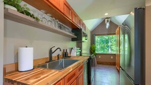 A modern kitchen with wooden cabinets, a stainless steel sink, and a built-in oven. - Tranquil Heights Cabin In Hocking Hills- HOT Tub! (Ray)