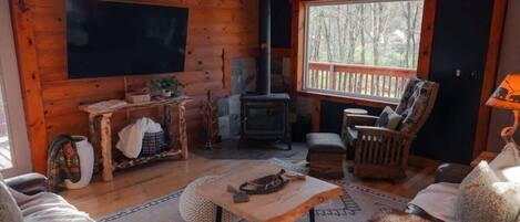 Un acogedor interior de cabaña con techo de madera, chimenea, sofás de cuero y televisor de pantalla plana.