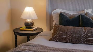 A neatly made bed with a patterned blanket, a bedside lamp, and a decorative wall piece.