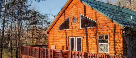 A log cabin with a metal roof, a deck, and a large window.